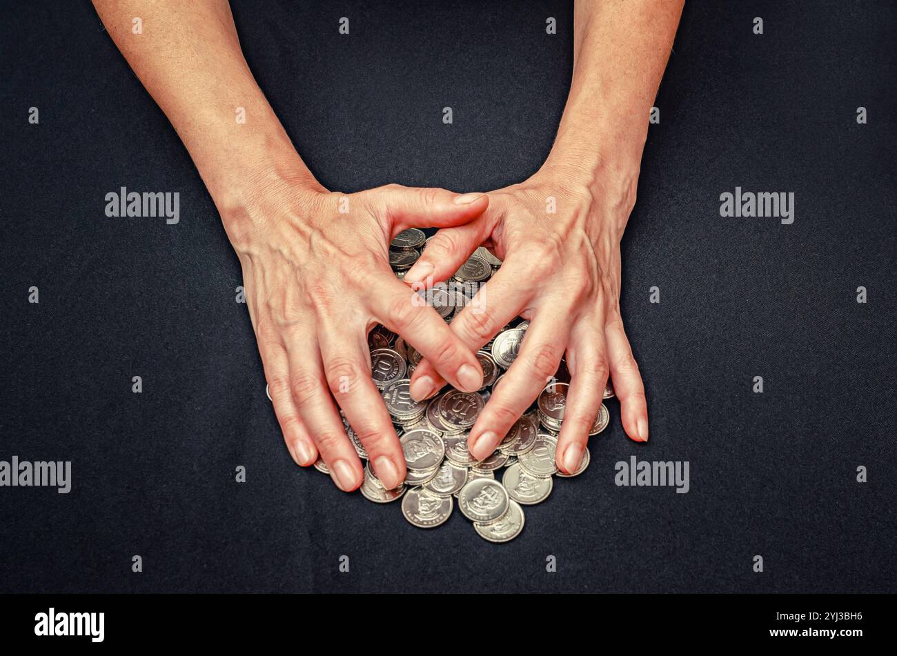 Le mani coprono mucchi di monete d'argento. Primo piano sul concetto di furto, appropriazione indebita, frode e avidità Foto Stock