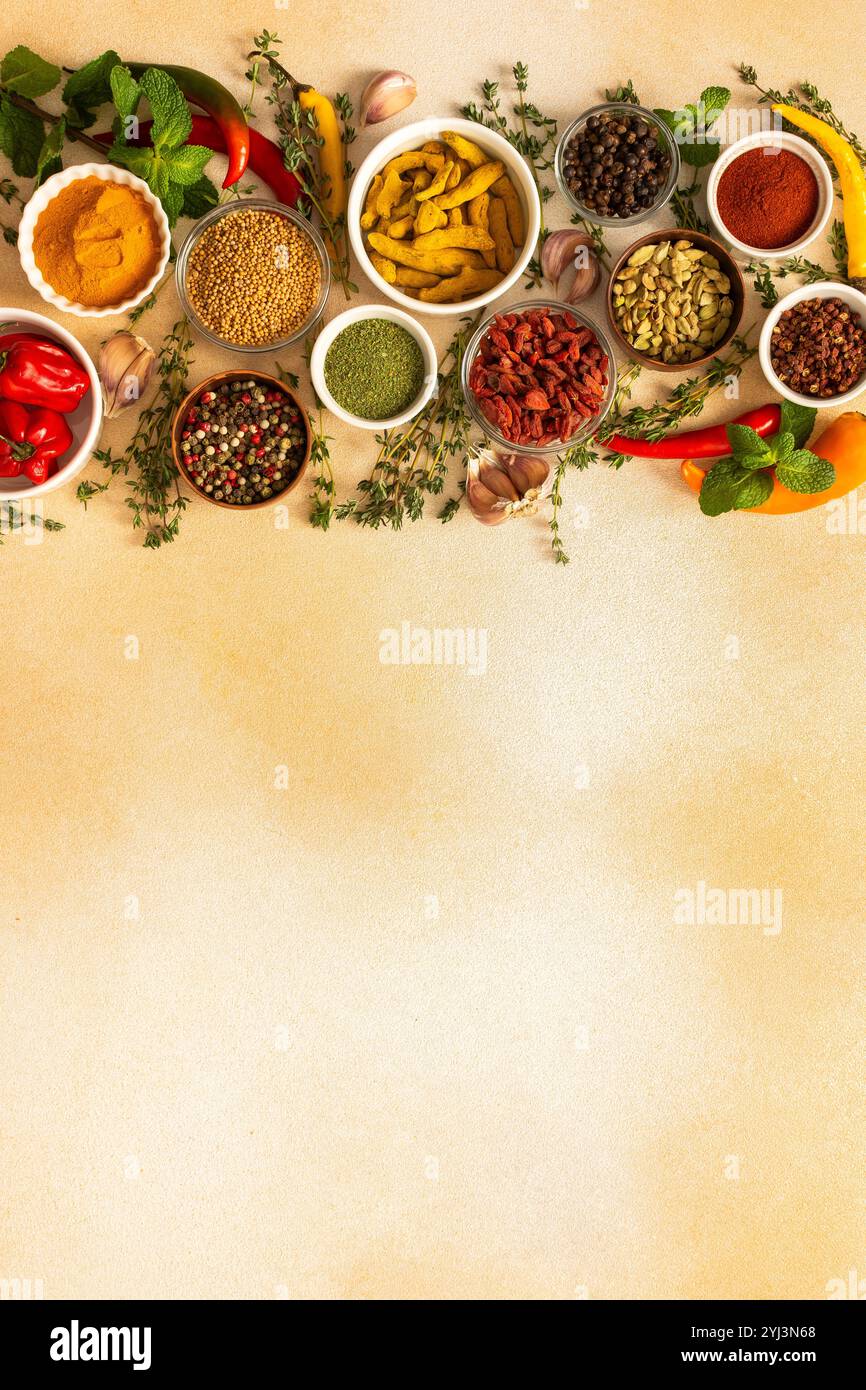 Una variopinta gamma di spezie secche ed erbe fresche disposte su un morbido sfondo beige, ideale per condire e aggiungere un ricco sapore ai piatti, vista dall'alto, Foto Stock