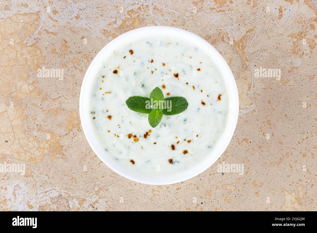 Salsa di raita indiana con yogurt, cetrioli e menta su sfondo giallo. Vista dall'alto. Salsa tzatziki greca. Cucina indiana Foto Stock