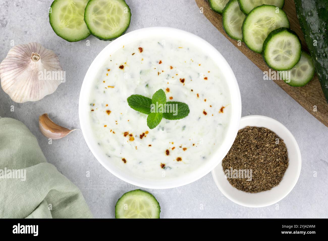 Salsa di raita indiana con yogurt, cetrioli ed erbe aromatiche su sfondo grigio. Vista dall'alto. Cibo indiano. Foto Stock