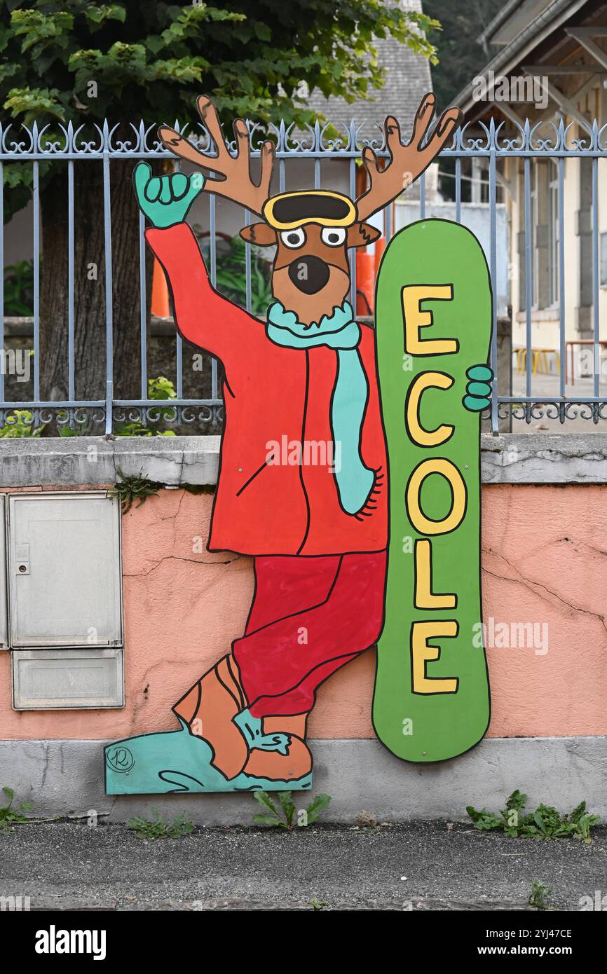 Cartoon Deer, Fun or Funny Sign of Dressed Deer in Winter Clothes Outside French School Campan Hautes-Pyrénées France Foto Stock