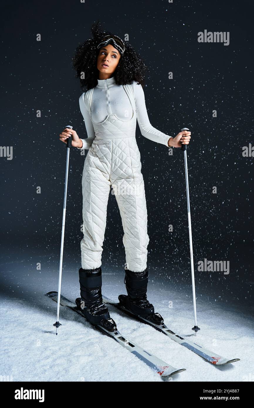 Una bella donna bruna modella un elegante costume da sci, catturando l'essenza dell'eleganza invernale in uno studio. Foto Stock