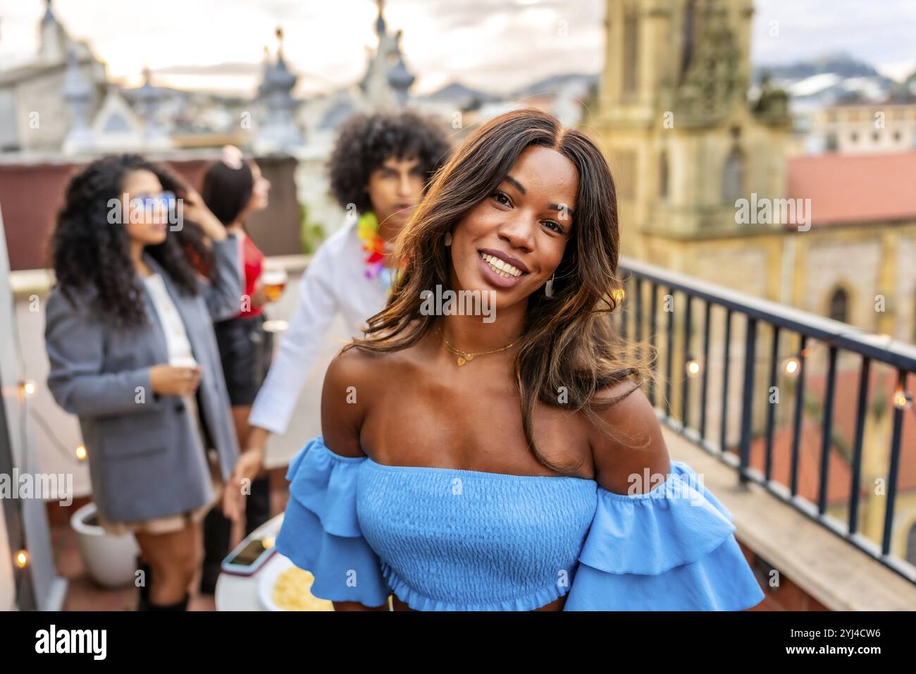 Elegante donna di bellezza in abito estivo che sorride mentre gli amici fanno festa all'aperto Foto Stock