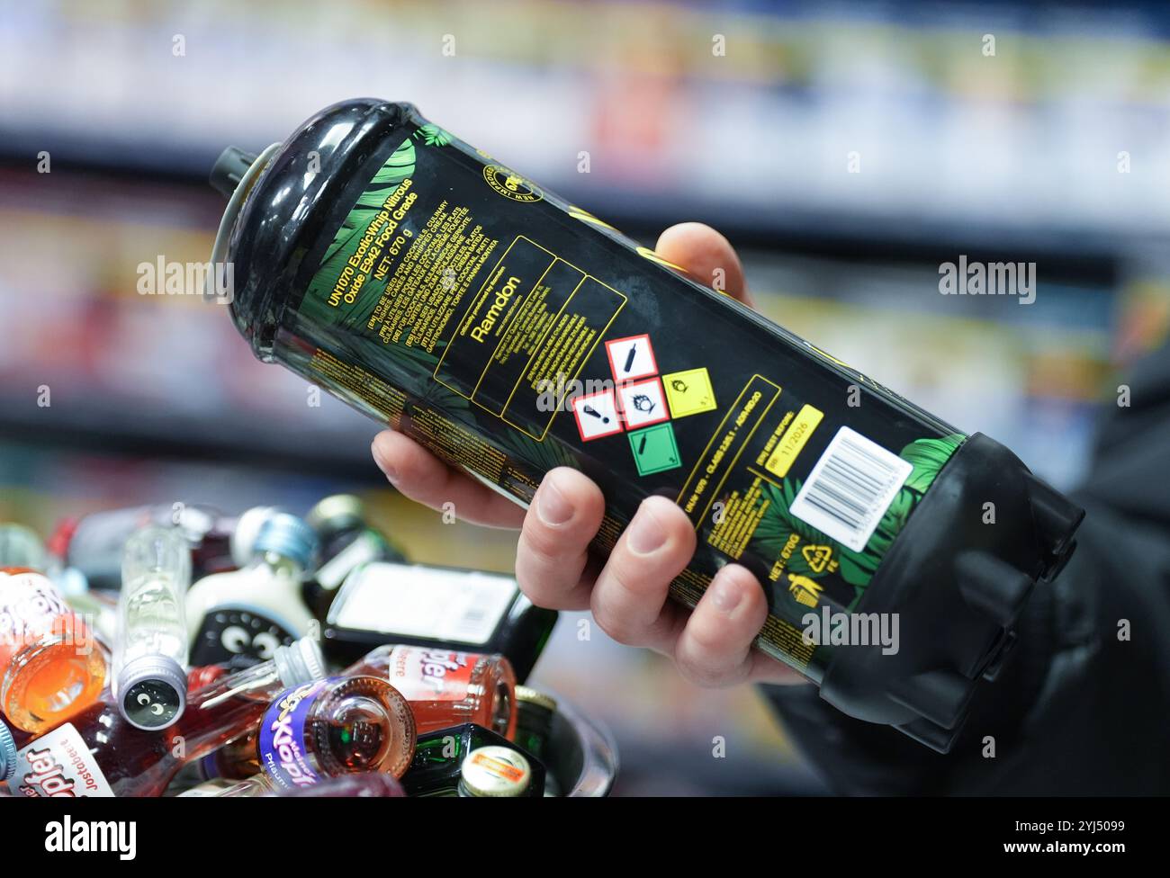 Amburgo, Germania. 13 novembre 2024. ILLUSTRAZIONE - un dipendente ha in mano una lattina di gas ridendo al bancone di un chiosco. L'uso di gas ridendo come droga da festa, soprattutto tra i giovani, potrebbe presto essere vietato in Germania. Il governo federale ha approvato un progetto del ministro della salute Lauterbach (SPD), che prevede anche un divieto di distribuzione tramite distributori automatici e negozi notturni. Crediti: Marcus Brandt/dpa/Alamy Live News Foto Stock