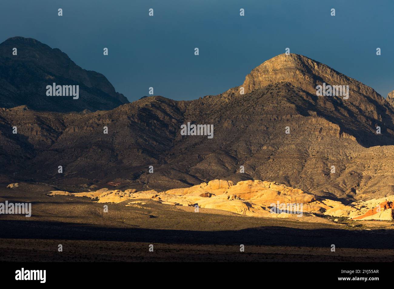 Montagne ombreggiata innalzarsi al di sopra delle soleggiate colline di Calico, il Red Rock Canyon National Conservation Area, Nevada Foto Stock