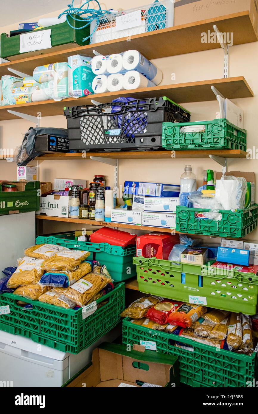 Scaffali pieni di cibo e lattine in una banca alimentare pronti per essere distribuiti alle famiglie che lottano per far fronte all'attuale crisi finanziaria Foto Stock