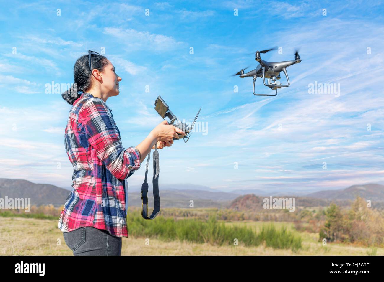 Una giovane donna controlla un drone. Foto Stock