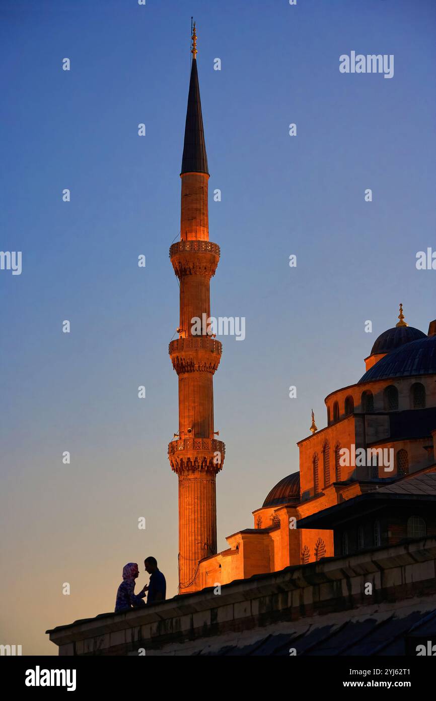 Una coppia romantica al tramonto si staglia vicino a un minareto della Moschea Blu di Istanbul, Turkiye. Foto Stock