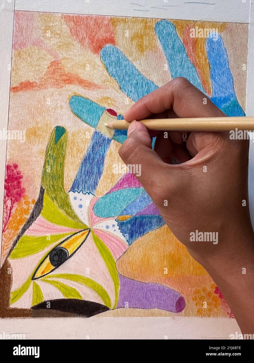 Una foto ravvicinata di una persona adulta ha realizzato un disegno di mani colorate usando una matita colorata su una carta d'archivio. - Immagine stock catturata con smartphone