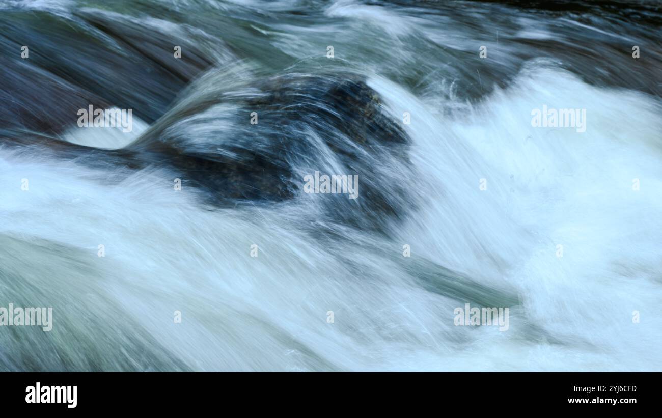 Primo piano al rallentatore dell'acqua fresca di montagna che scorre sulla roccia del fiume Foto Stock