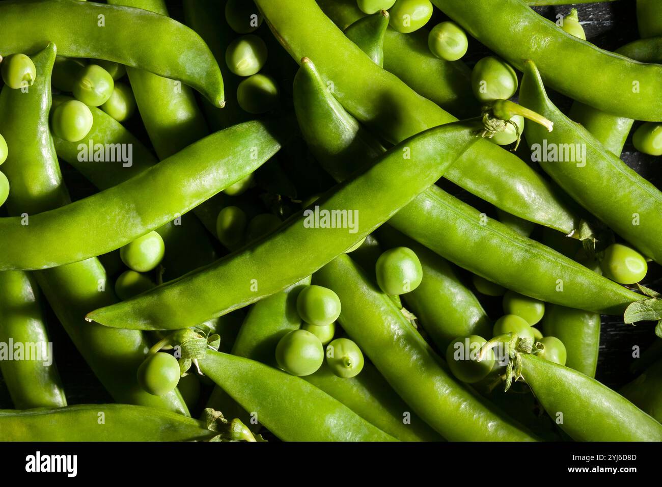piselli verdi su sfondo in legno nero Foto Stock