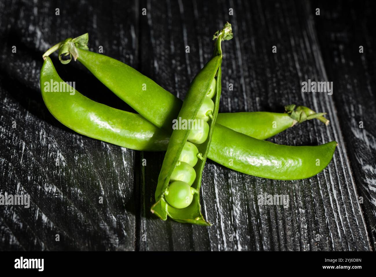 apri piselli verdi su sfondo di legno nero Foto Stock