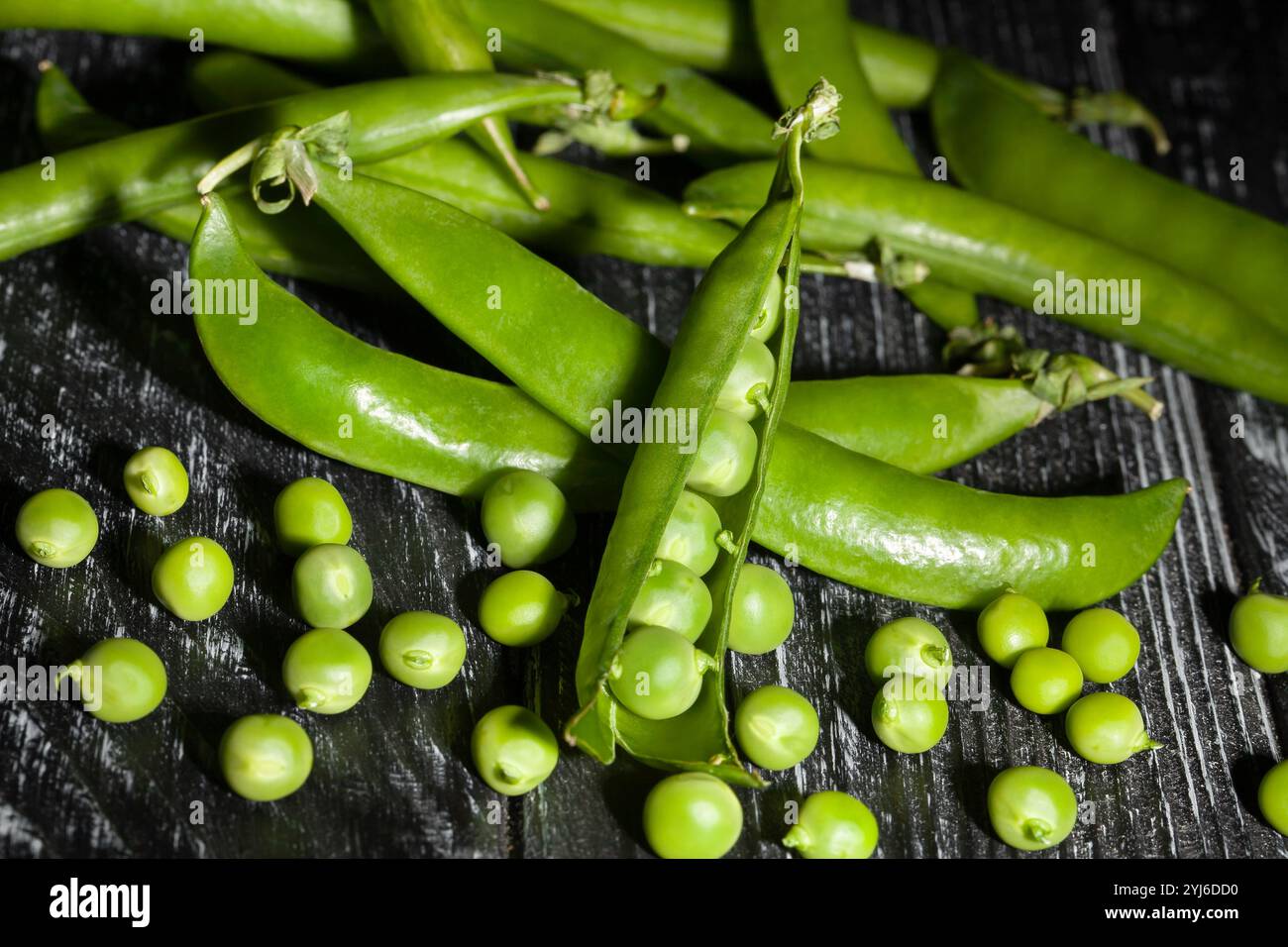 apri piselli verdi su sfondo di legno nero Foto Stock