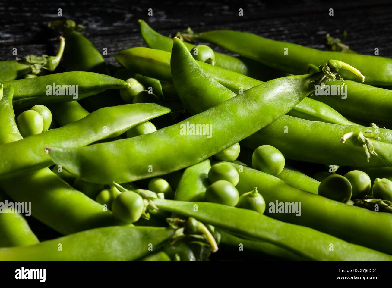 piselli verdi su sfondo in legno nero Foto Stock