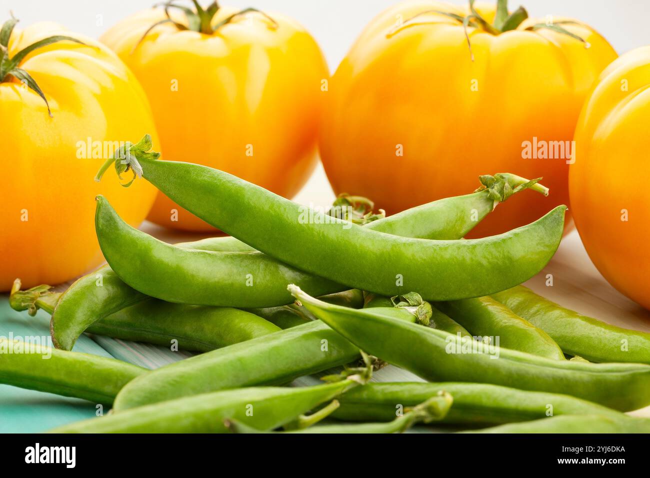 piselli verdi pomodoro giallo su legno Foto Stock