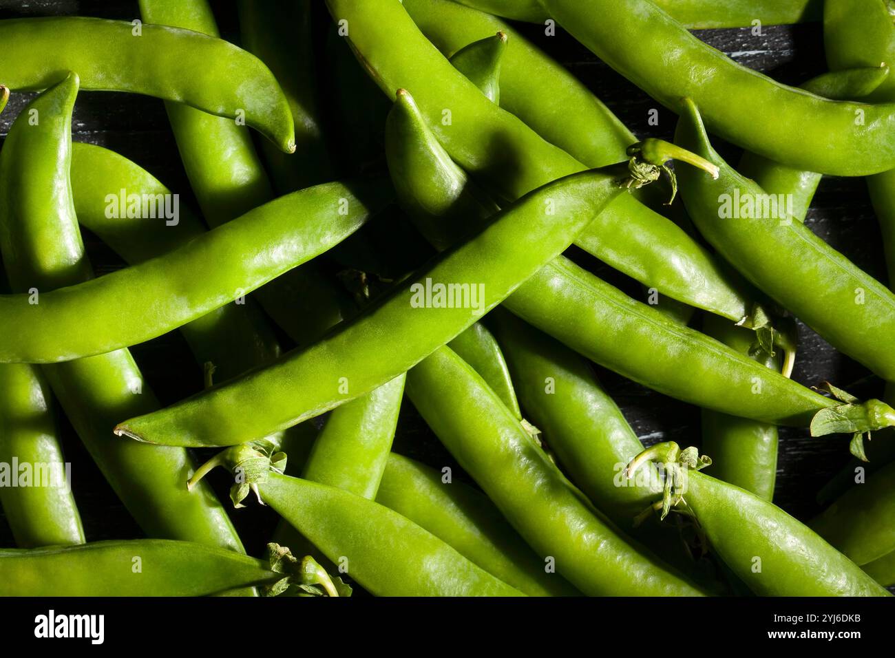 piselli verdi su sfondo in legno nero Foto Stock