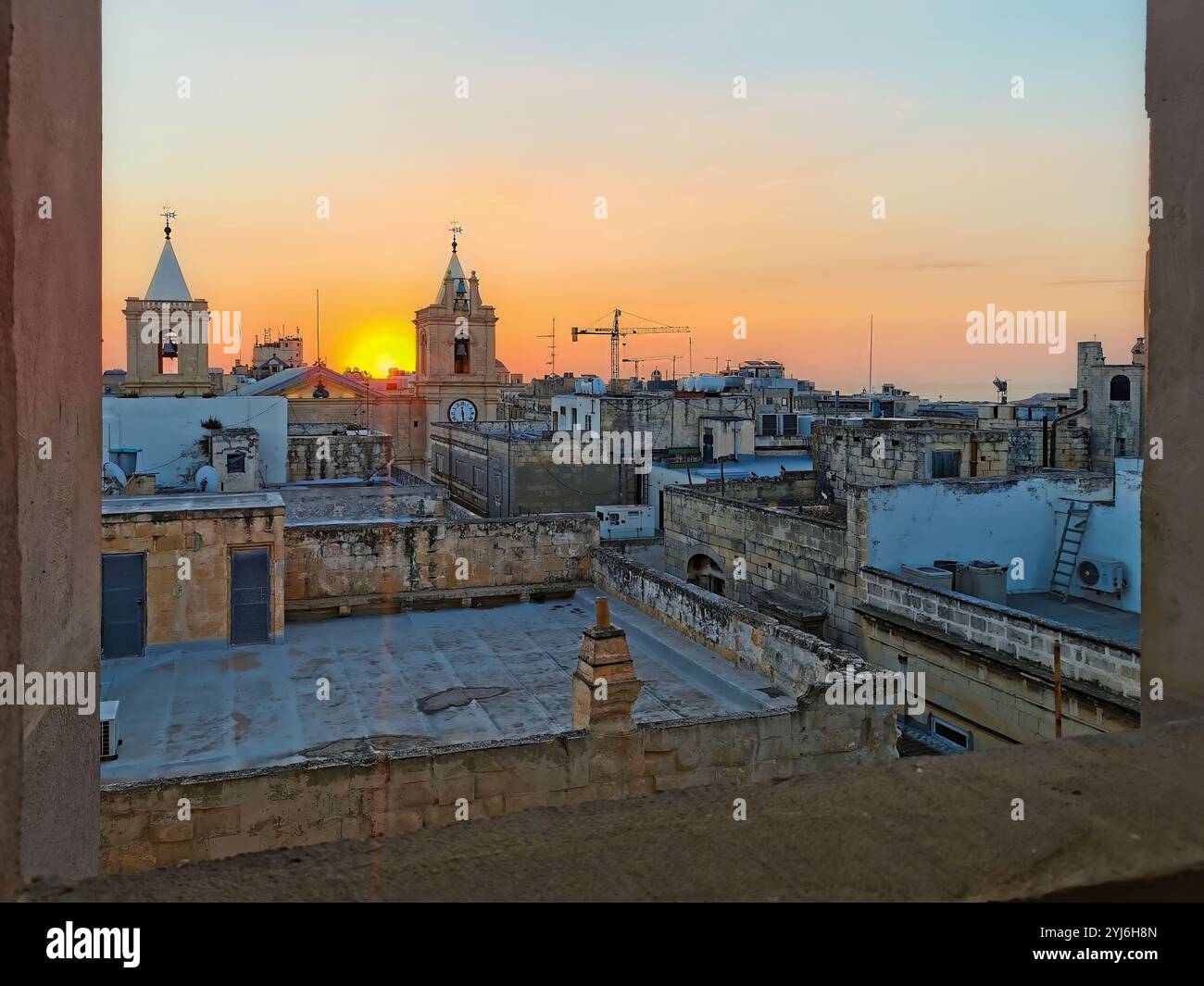 Alba sui tetti e sui campanili di la Valletta, Malta, che getta un caldo bagliore sull'architettura storica. Foto Stock