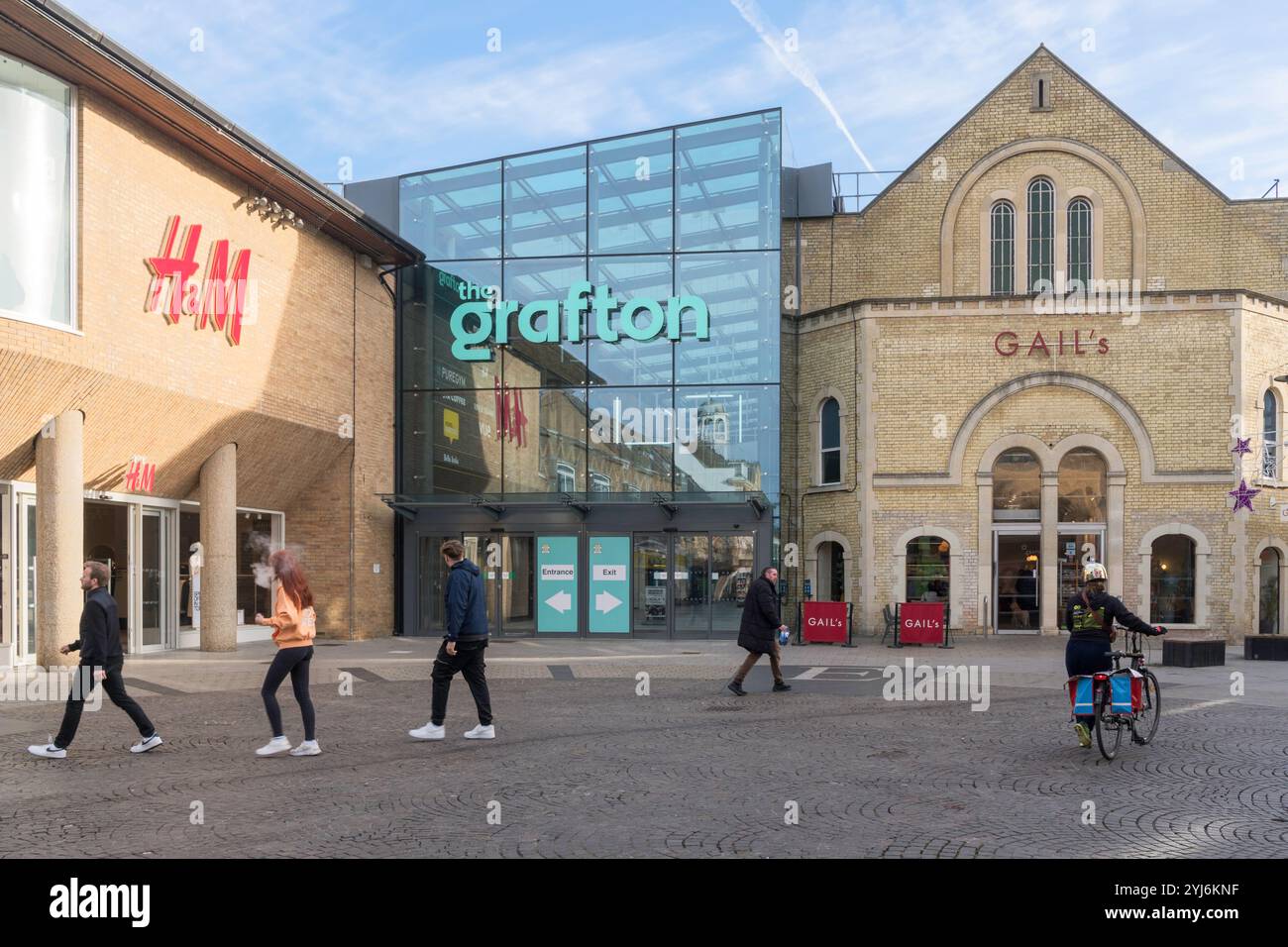 Persone che attraversano Fitzroy Street fuori dal centro commerciale Grafton a Cambridge, Inghilterra, Regno Unito Foto Stock