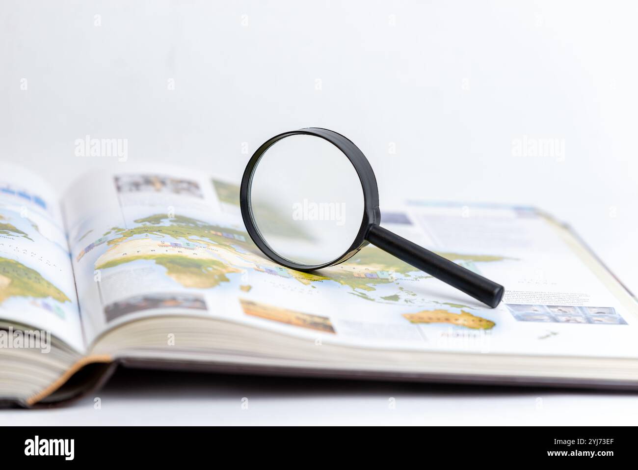 Lente d'ingrandimento su un libro aperto che simboleggia la ricerca, la ricerca e l'esplorazione approfondita di conoscenze e informazioni, enfatizzando la scoperta e i dettagli Foto Stock