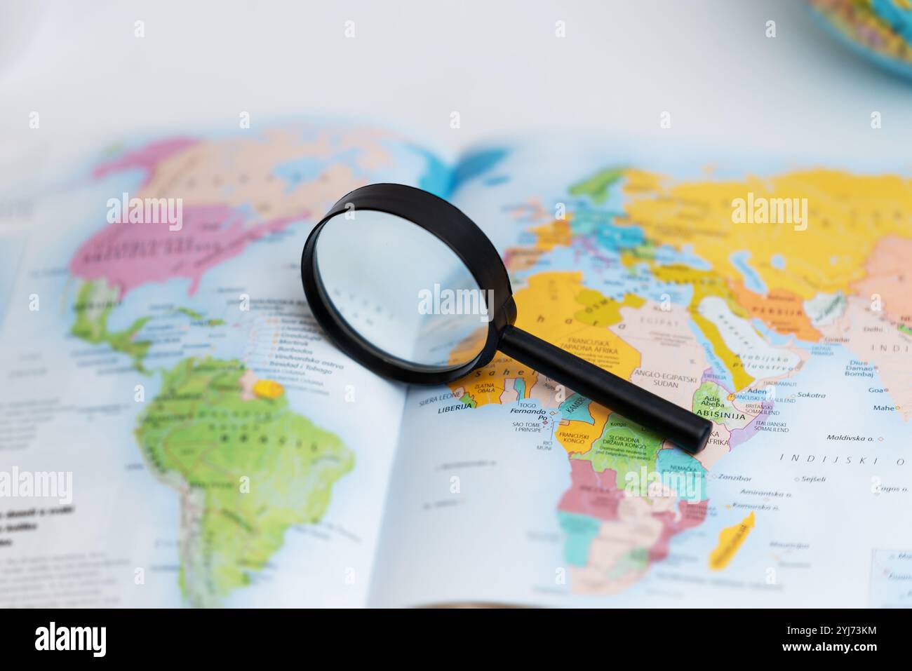 Lente di ingrandimento sulla mappa atlas, che simboleggia la ricerca di viaggi, l'esplorazione geografica, la scoperta globale e la pianificazione della navigazione Foto Stock