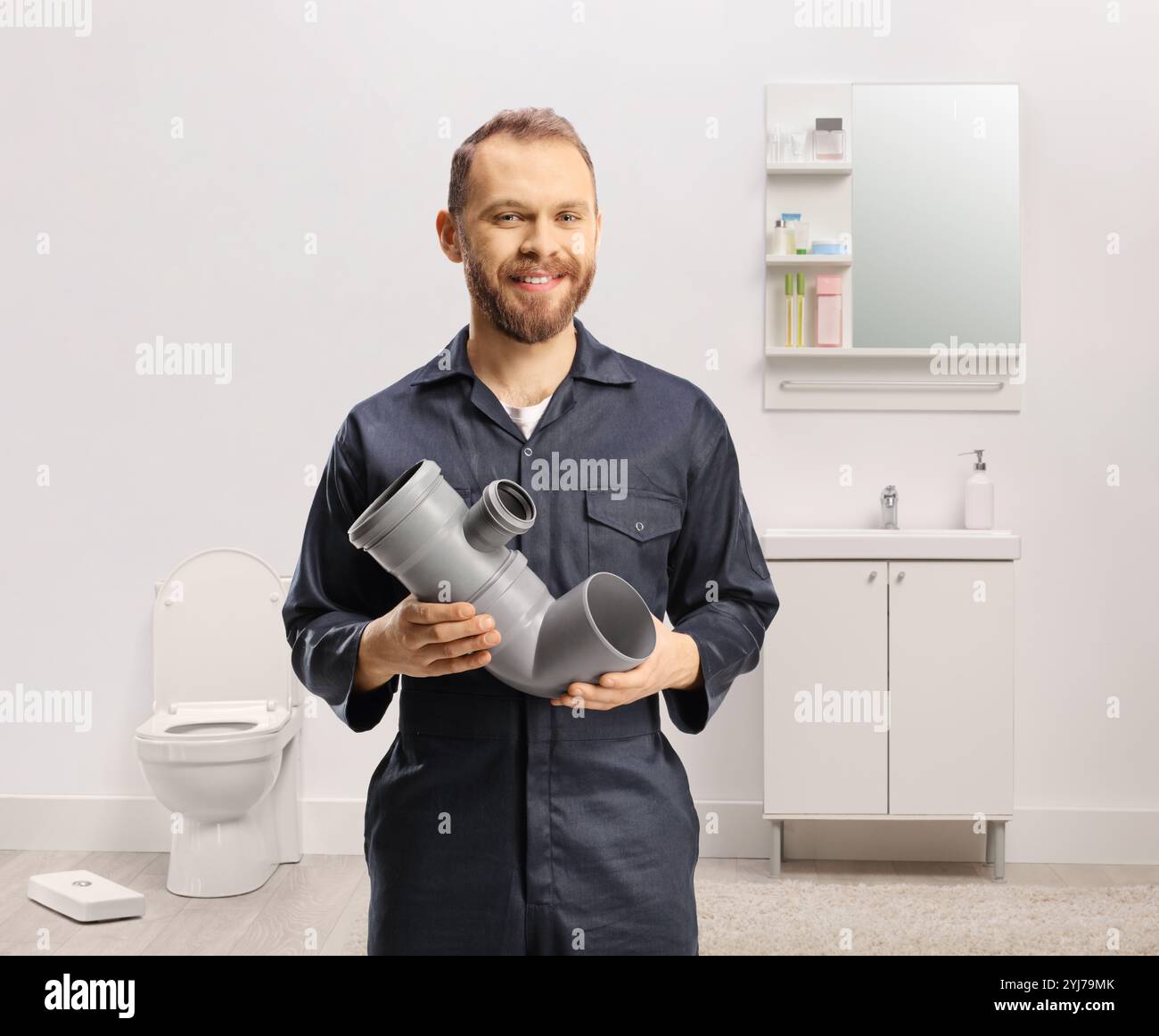 Idraulico in uniforme che tiene una pipa in bagno Foto Stock