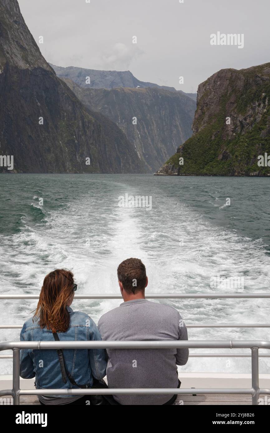 Una coppia si gode la vista delle montagne e delle scogliere durante una crociera attraverso Milford Sound e Doubtful Sound. Foto Stock