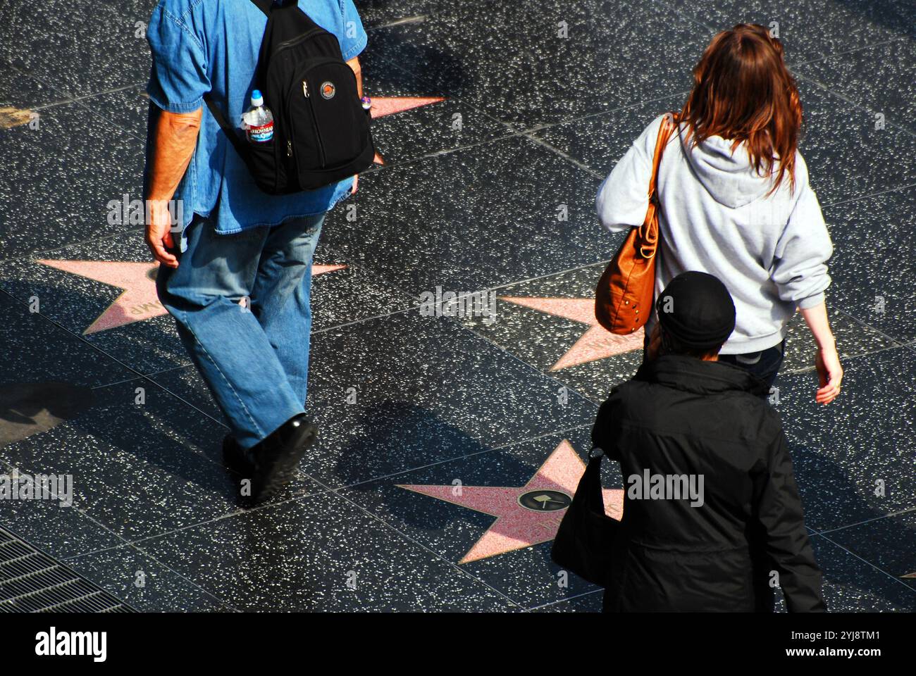 Le persone camminano e guardano le stelle delle loro star del cinema preferite e degli animatori sul marciapiede lungo Hollywood Boulevard a Hollywood, California Foto Stock