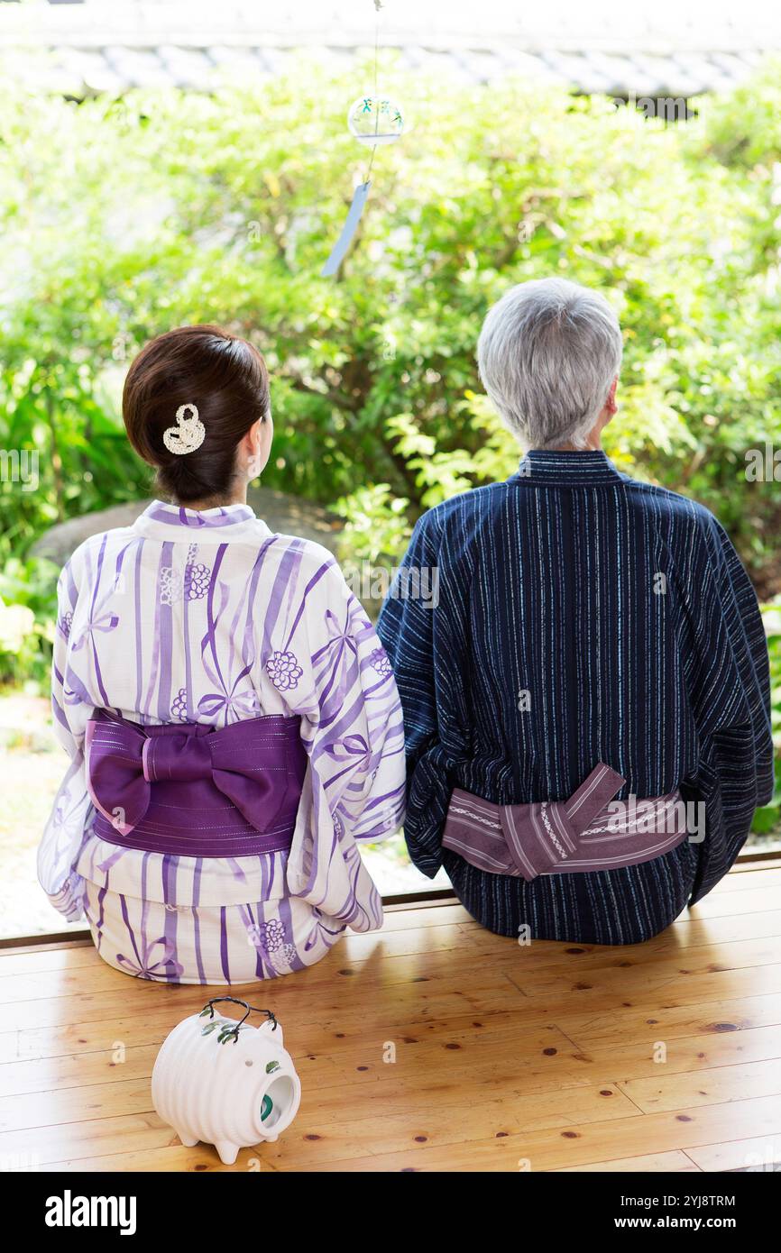 Coppia di mezza età in yukata sulla veranda, vista posteriore Foto Stock