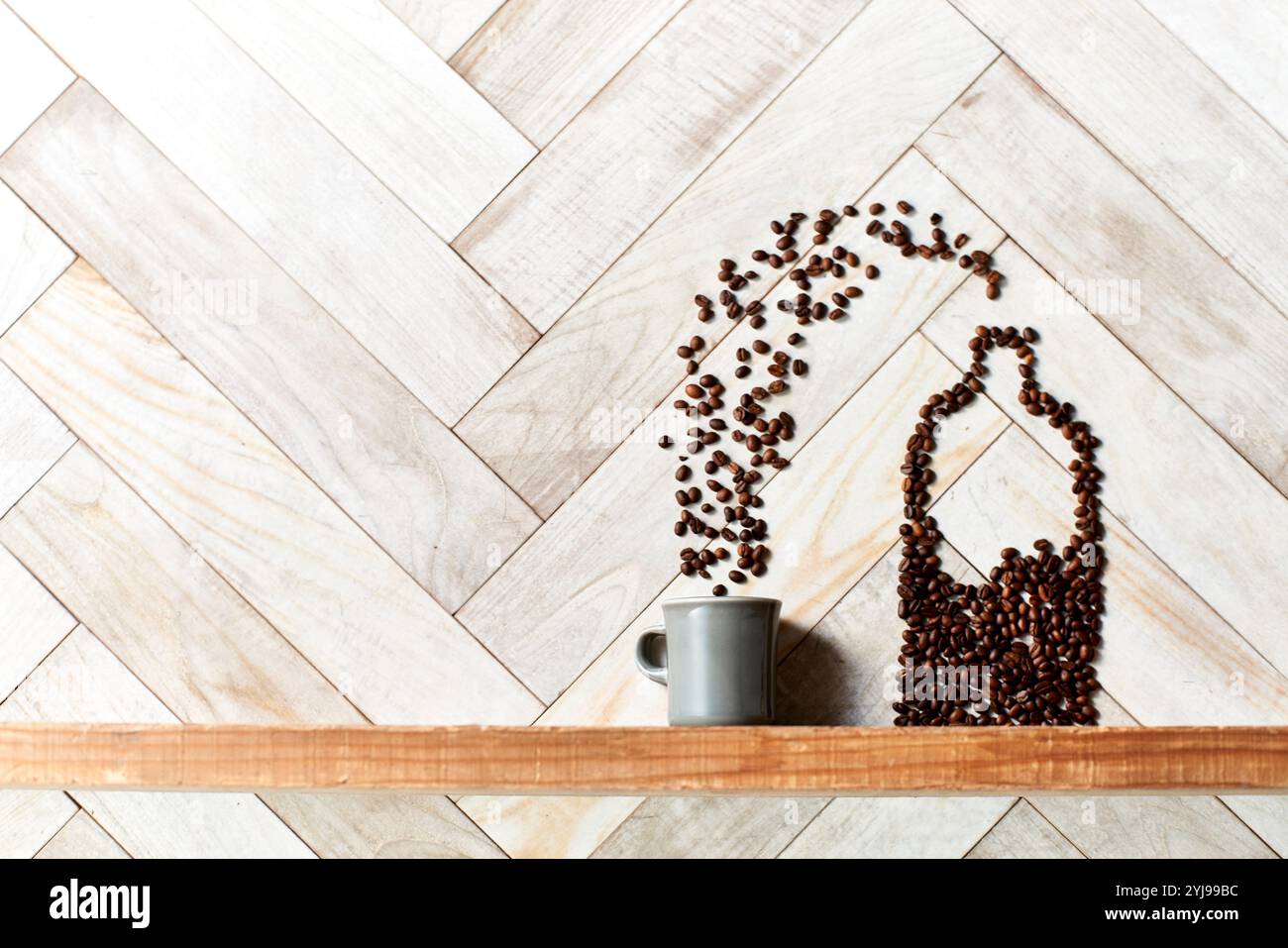Chicchi di caffè rilasciati da una bottiglia di chicchi di caffè formati su un ripiano di legno in una tazza Foto Stock