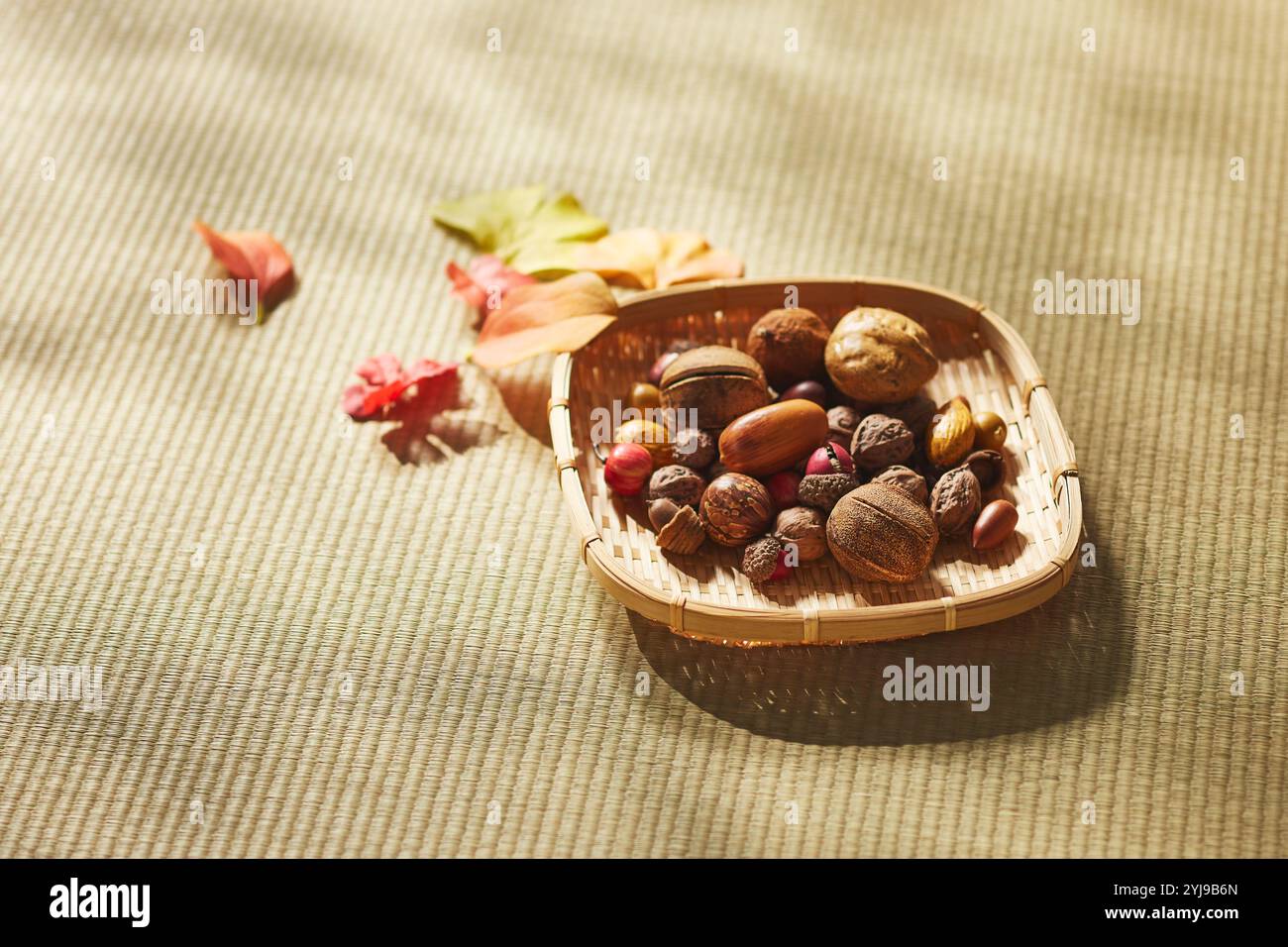 Noci e foglie cadute in un colino su un tappetino tatami Foto Stock