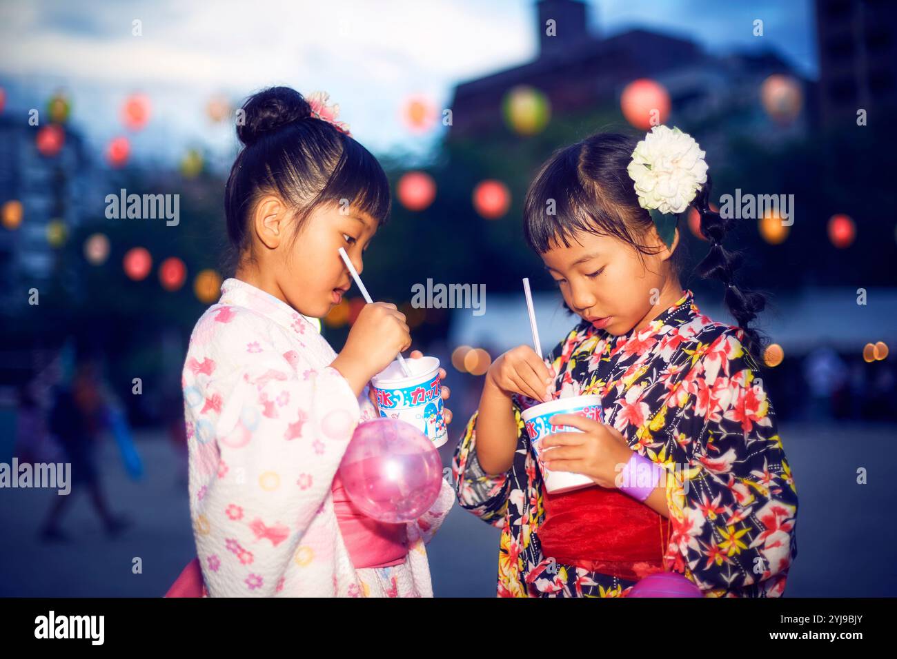 Ragazza nello yukata che mangia il ghiaccio rasato comprato da un bancone del festival Foto Stock