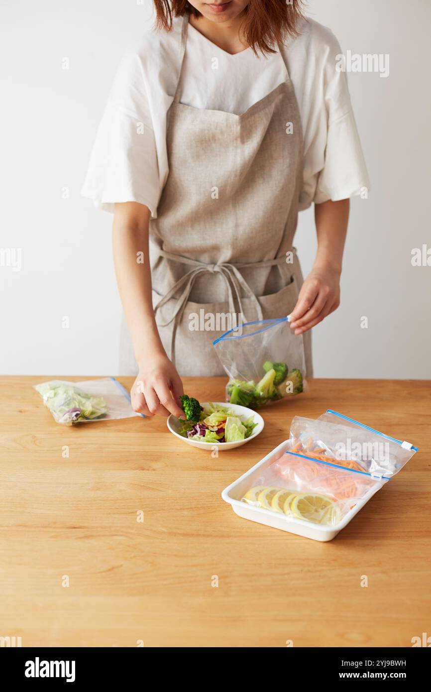 Donna che rimuove le verdure dal sacchetto e serve l'insalata Foto Stock