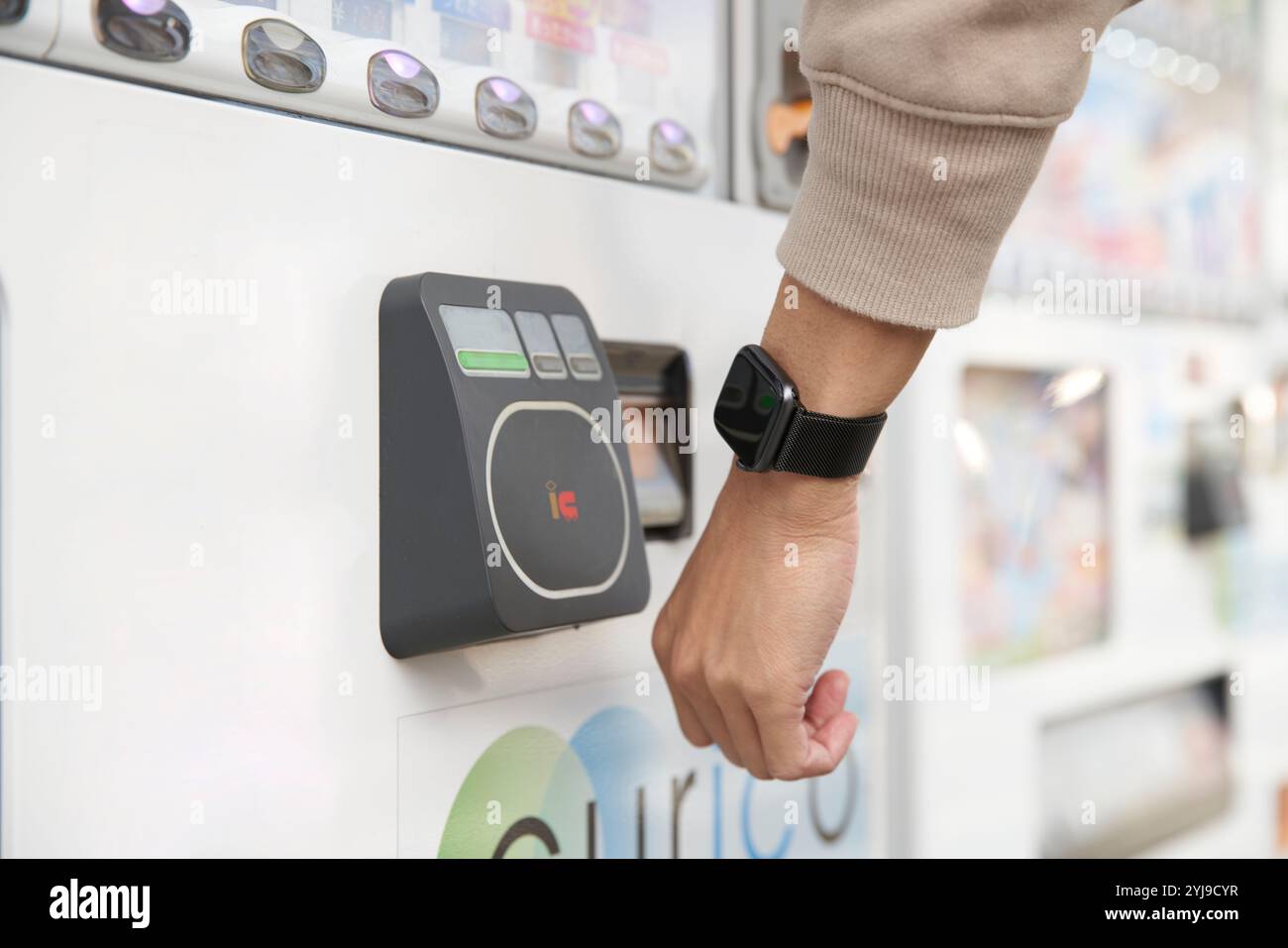 Uomo che tiene il suo smartwatch sopra un lettore di carte presso un distributore automatico Foto Stock