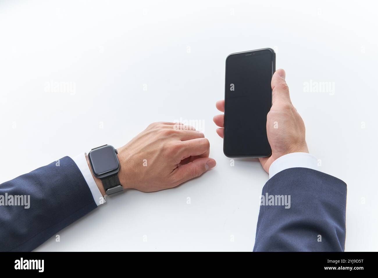 Uomo con un abito che indossa uno smartwatch e tiene uno smartphone nella mano destra Foto Stock