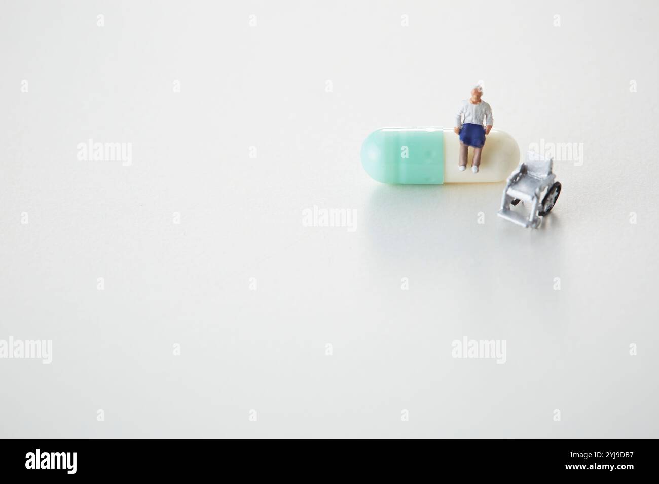 Vecchio e sedia a rotelle seduti su capsule medicine Foto Stock