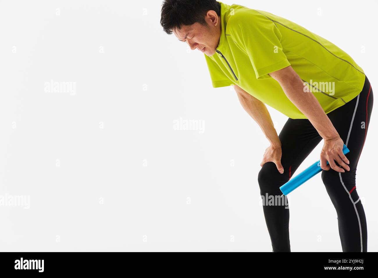 Un atleta maschile in pista e sul campo in ginocchio, stanco dopo aver eseguito la staffetta Foto Stock
