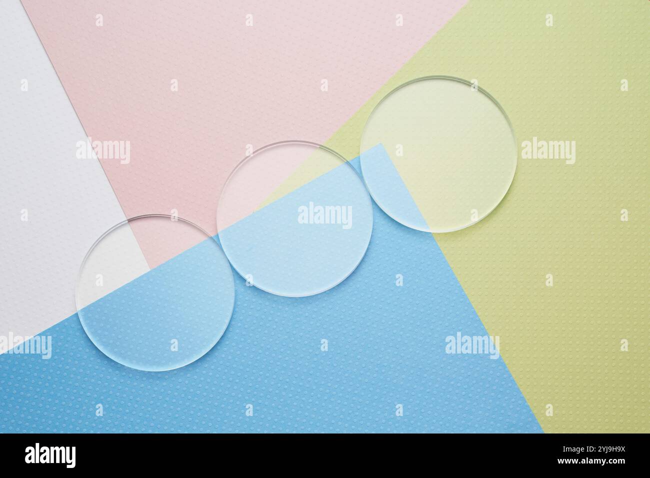 3 bicchieri rotondi allineati su 4 strati di carta colorati Foto Stock