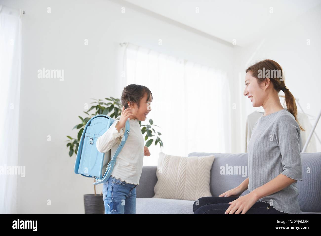 Bambino e madre si preparano per la scuola in salotto Foto Stock