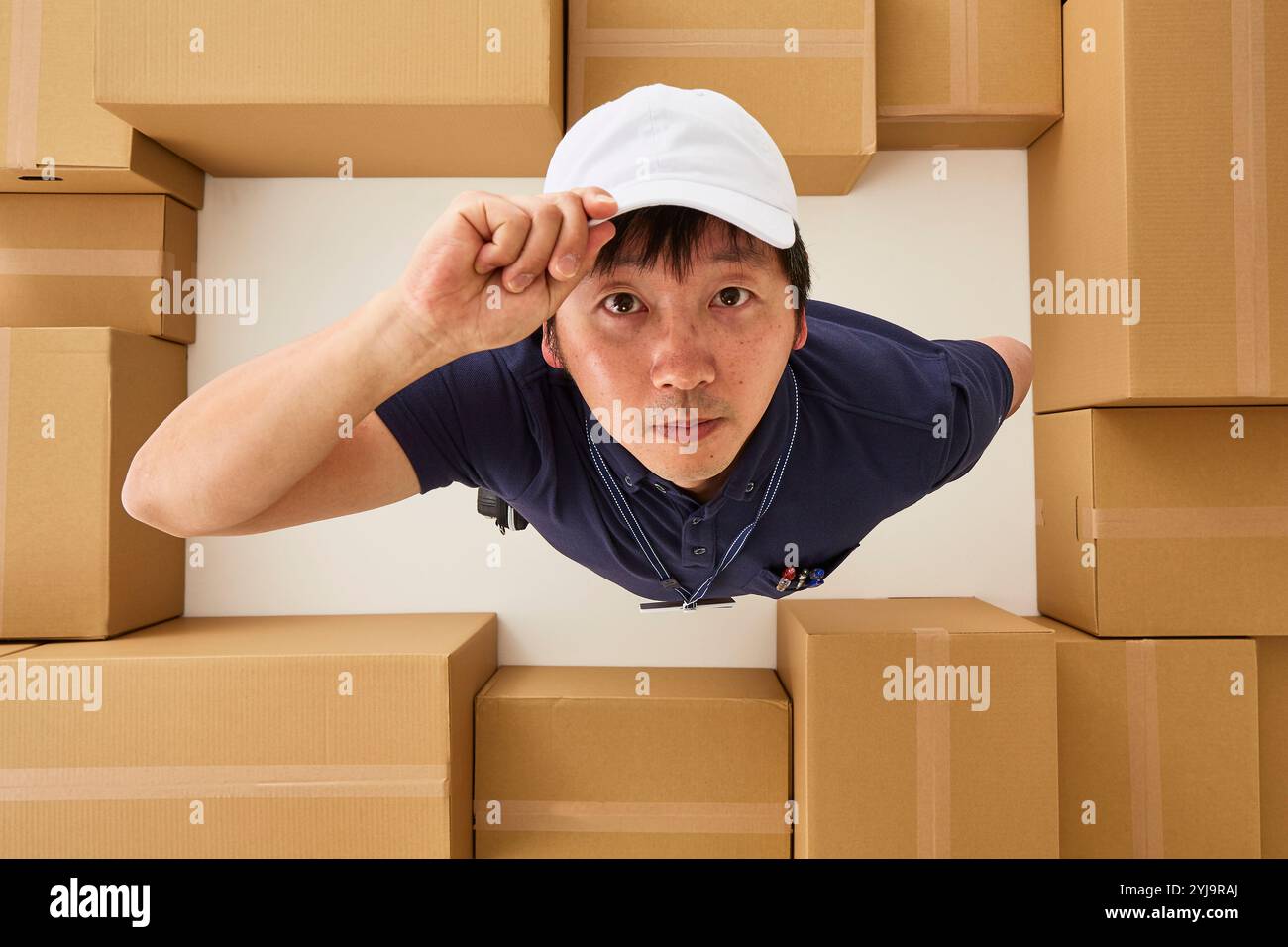 Uomo in abiti da lavoro che guarda la macchina fotografica nello spazio circondato da scatole di cartone Foto Stock