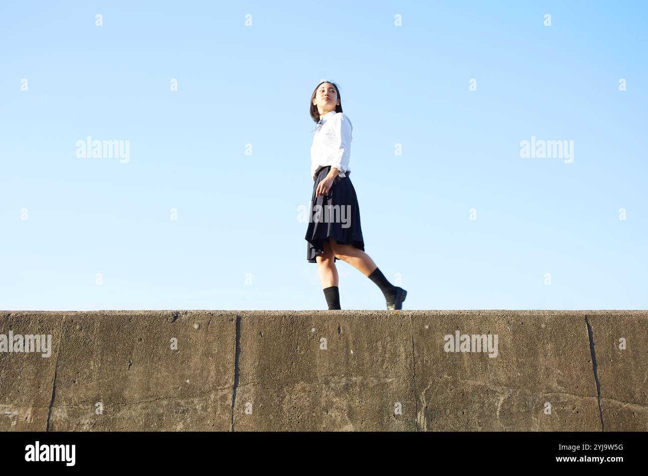 Ragazza delle superiori che cammina su un argine Foto Stock