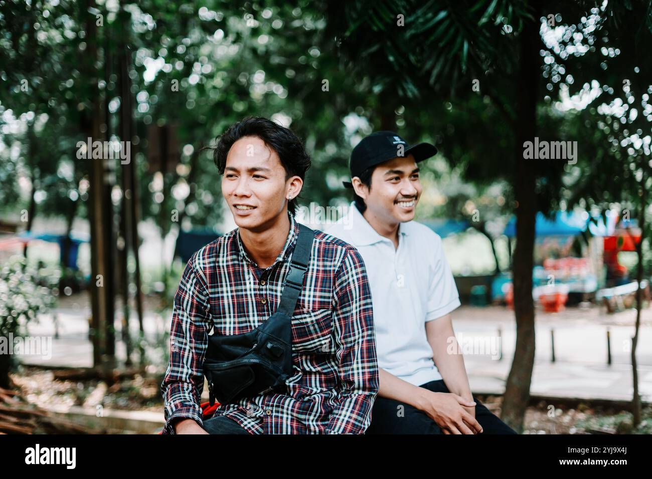 Due uomini del sud-est asiatico seduti in una piazza della città, catturano un momento di relax e conversazione. Ideale per progetti incentrati sulla vita urbana, comuni Foto Stock
