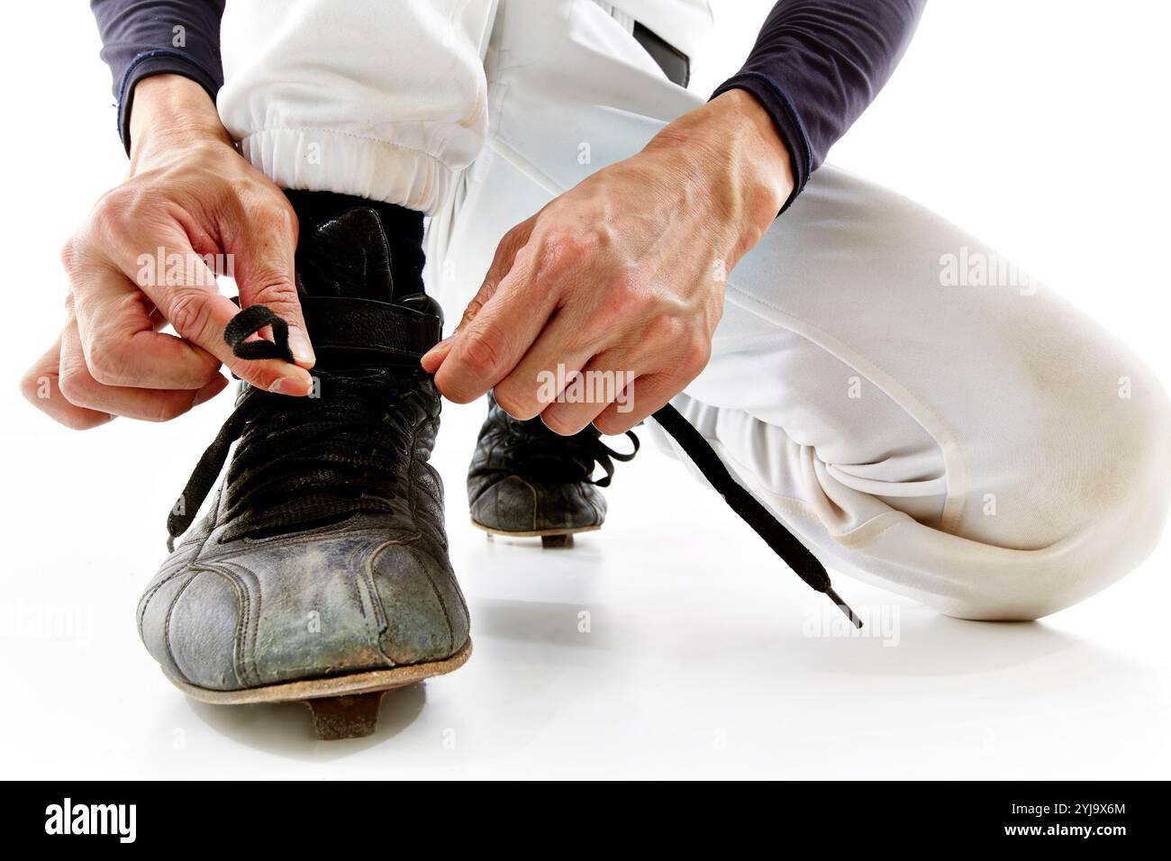 Uomo in uniforme da baseball che lega lacci per scarpe Foto Stock