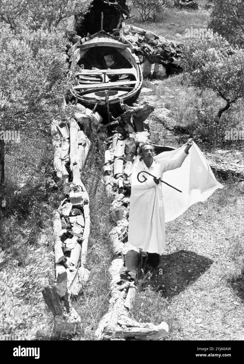 Salvador Dali, dipinto surrealista e scultore, sta con sua moglie abito billowing lui accanto alla sua figura gigantesca di Cristo che è costruito dalla guerra civile i detriti. Foto Stock