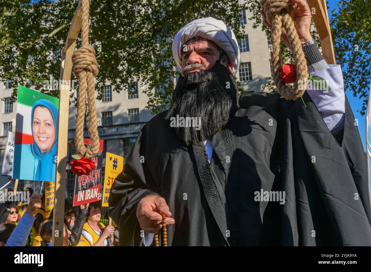 Londra, Regno Unito. 20 ottobre 2018. Un uomo vestito da Ayatollah accresce il nodo su un cappio. Dietro lo striscione "democrazia in Iran con Maryam Rajavi”, i Mujaheddin del popolo iraniano hanno protestato contro l'attuale regime repressivo in Iran, con una scommessa e tre donne detenute in una cella carceraria che illustra il regno del terrore e chiede la fine delle esecuzioni in quel paese, i manifesti ci hanno ricordato che il regime iraniano è detentore del record mondiale delle esecuzioni. Rajavi, leader del PMOI, ha elaborato un manifesto in 10 punti che chiede un sistema giuridico moderno, la parità di genere, la politica e la socia Foto Stock