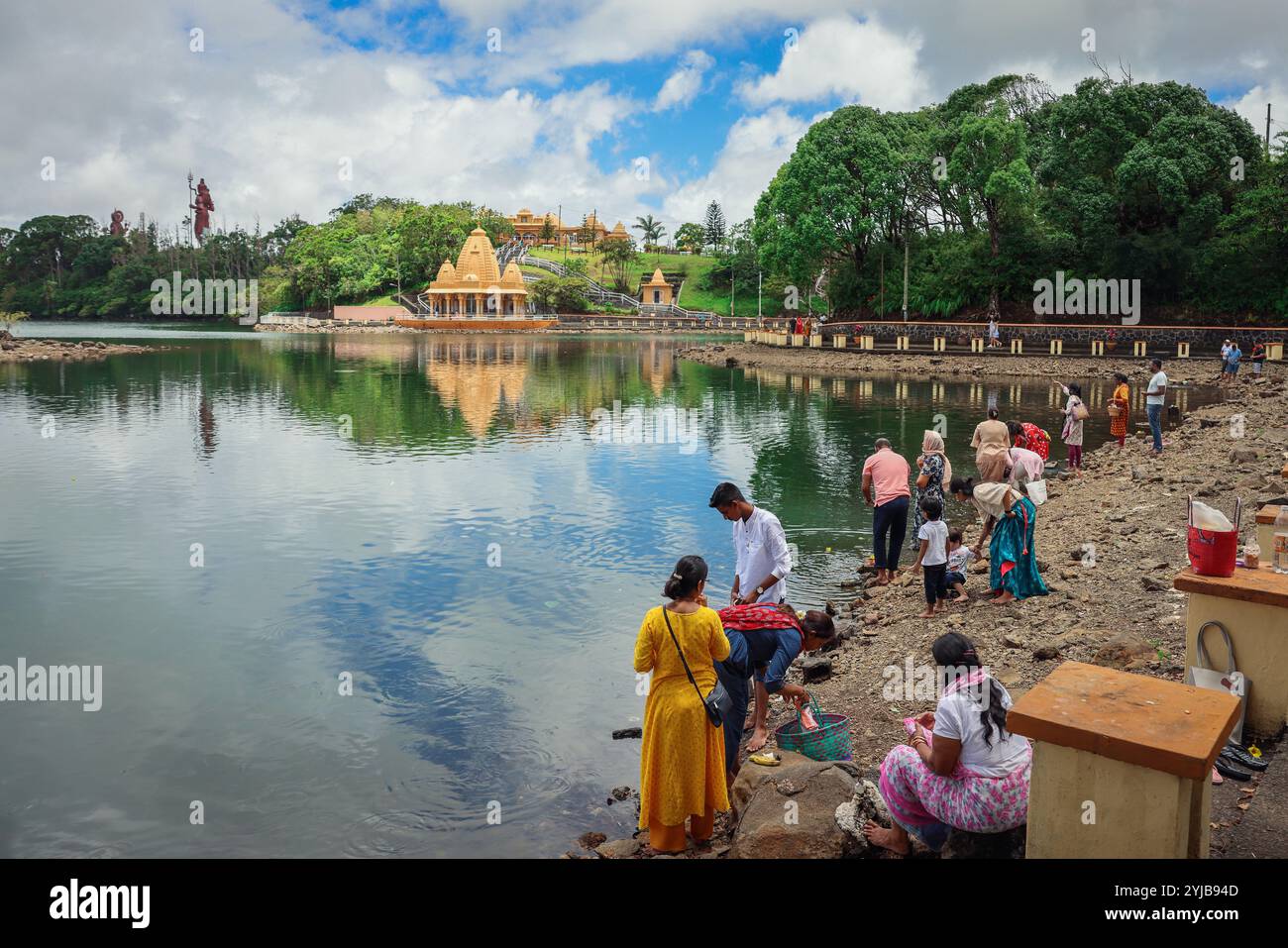 Un gruppo eterogeneo di individui, seguendo le tradizioni indù, si trova vicino alle acque di Mauritius. Foto Stock