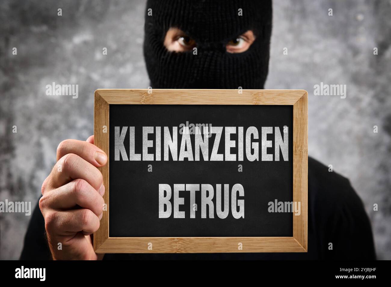 Baviera, Germania - 14 novembre 2024: Truffa dei Classifieds, scritta su un cartello di fronte a una persona anonima/sconosciuta mascherata. Immagine simbolica delle frodi su Internet tramite annunci pubblicitari e annunci come quelli Ebay. FOTOMONTAGGIO *** Kleinanzeigen Betrug, steht auf einem Schild vor maskierter anonymer / persona non bekannter. Symbolbild für Betrug im Internet über Inserate und Anzeigen wie Ebay Kleinanzeigen. FOTOMONTAGE Foto Stock