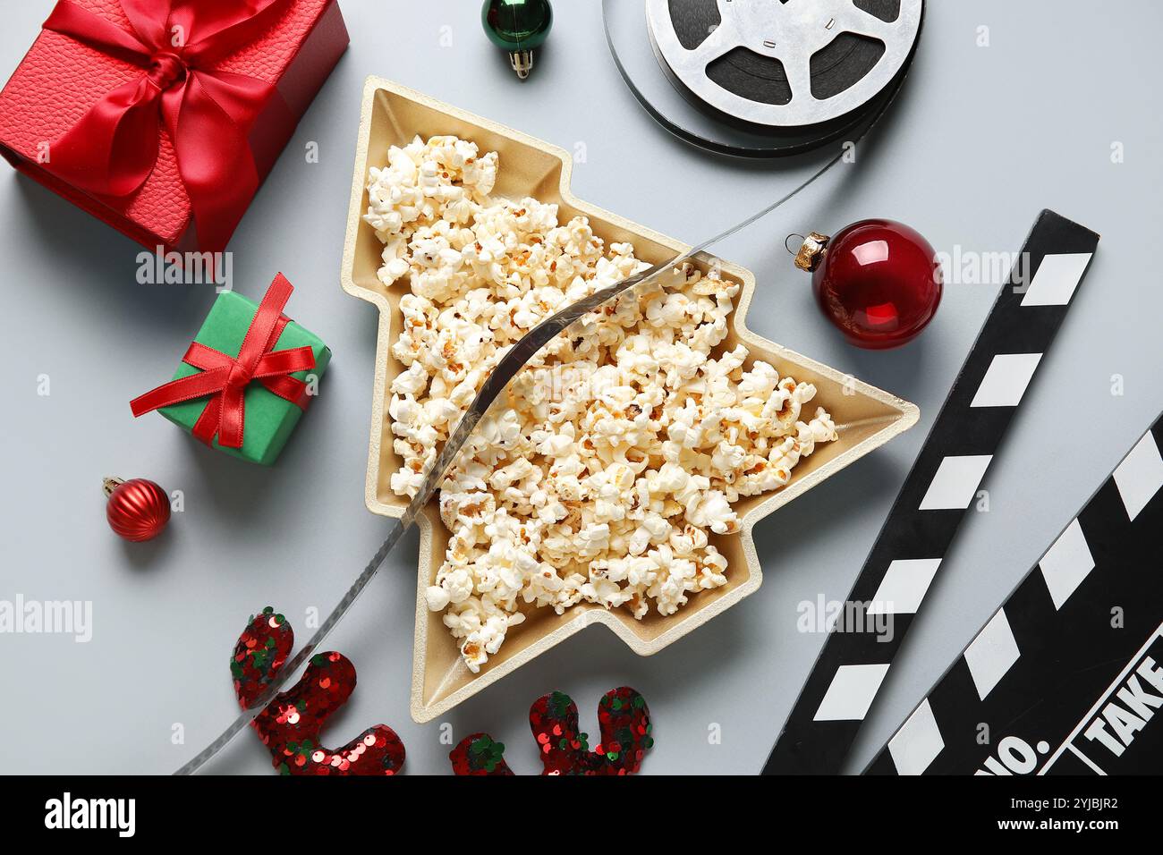Piatto a forma di albero di Natale con popcorn, film, clapper, scatole regalo e decorazioni natalizie su sfondo bianco Foto Stock