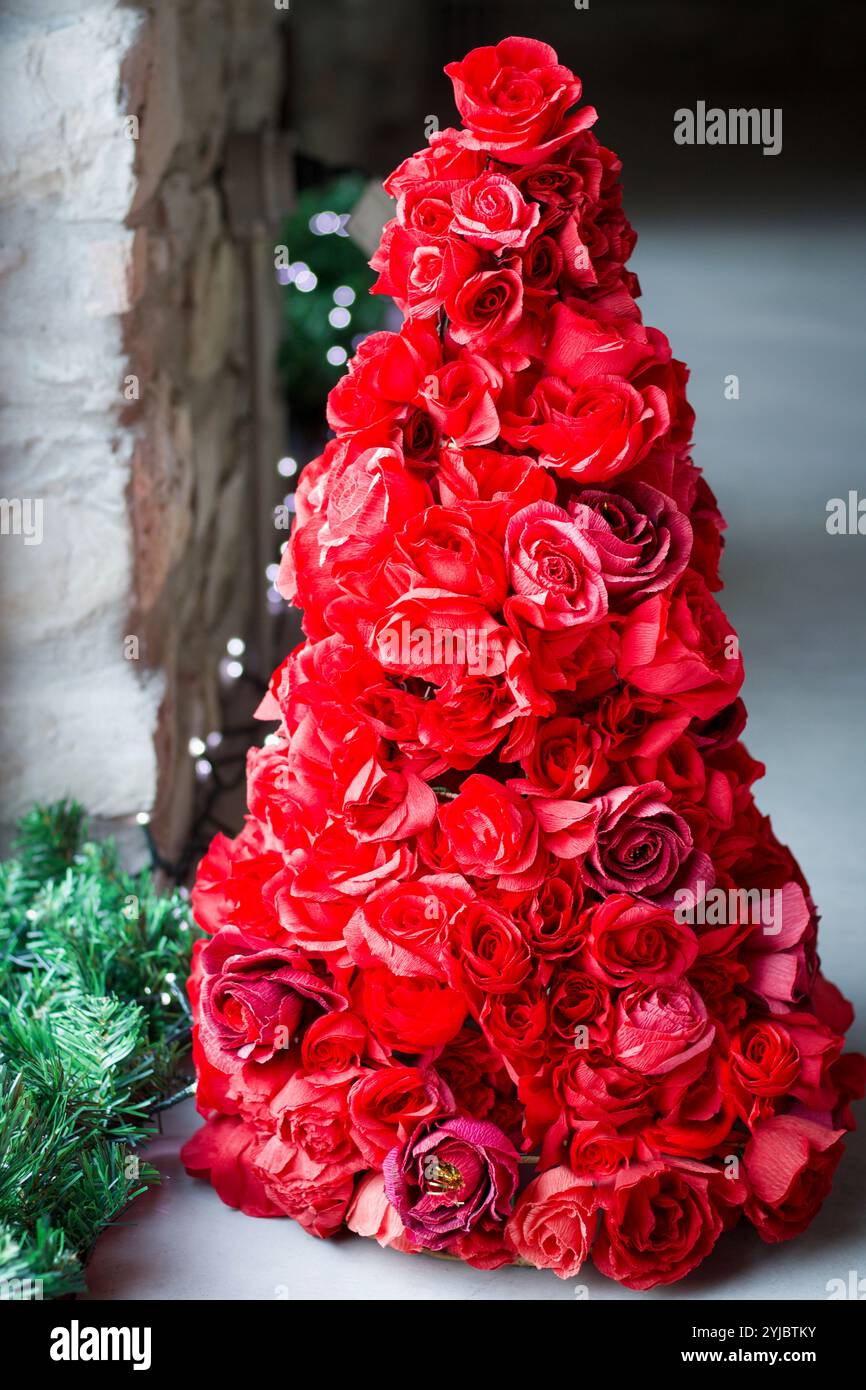 albero di natale fatto da un grande gruppo di carta rossa roses vicino a una finestra Foto Stock