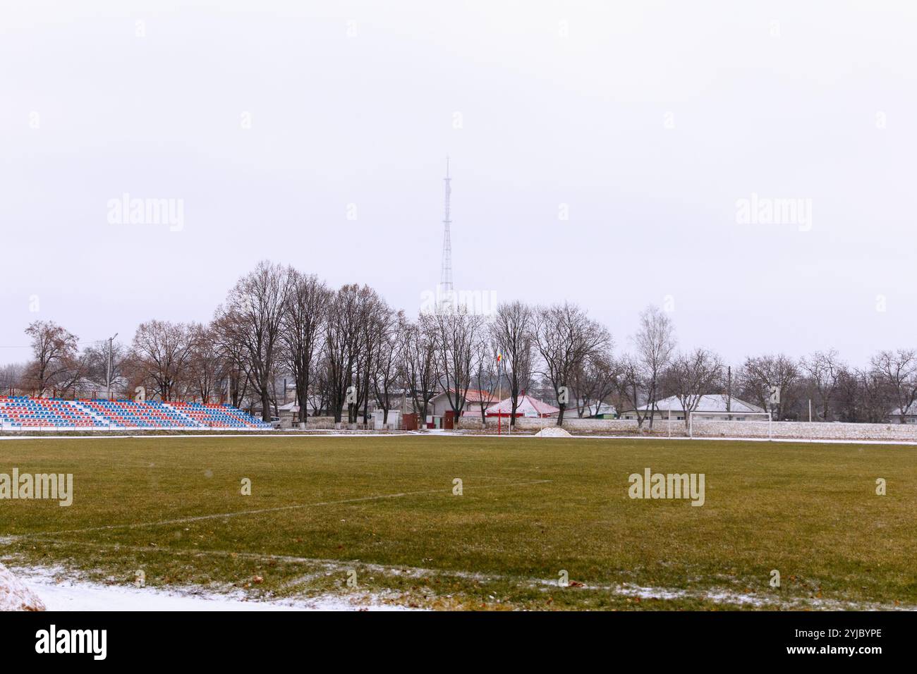 Revisione dello stadio sportivo. Tapis roulant, parte del campo da calcio e posti per i tifosi, all'aperto in inverno, sullo sfondo della torre della televisione Foto Stock