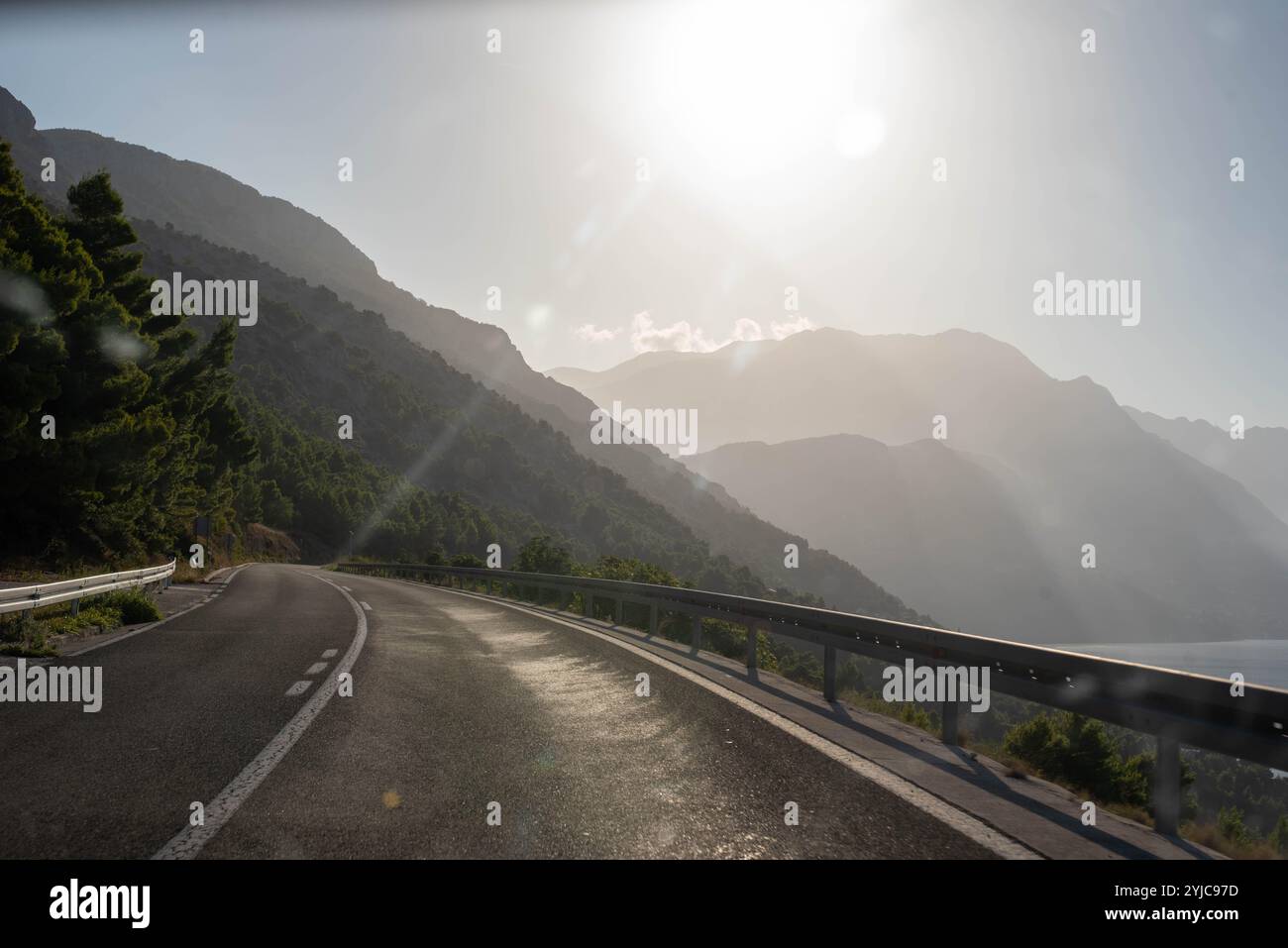 Strada di montagna nella regione della Dalmazia, Croazia, che si snoda attraverso paesaggi panoramici con vedute mozzafiato del terreno accidentato e della bellezza costiera. Un p Foto Stock